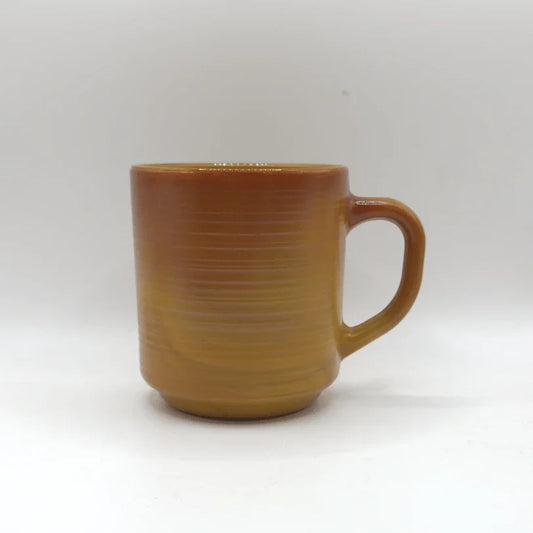 Bruine keramische koffiemok met rechte zijkanten en brede handgreep op witte achtergrond