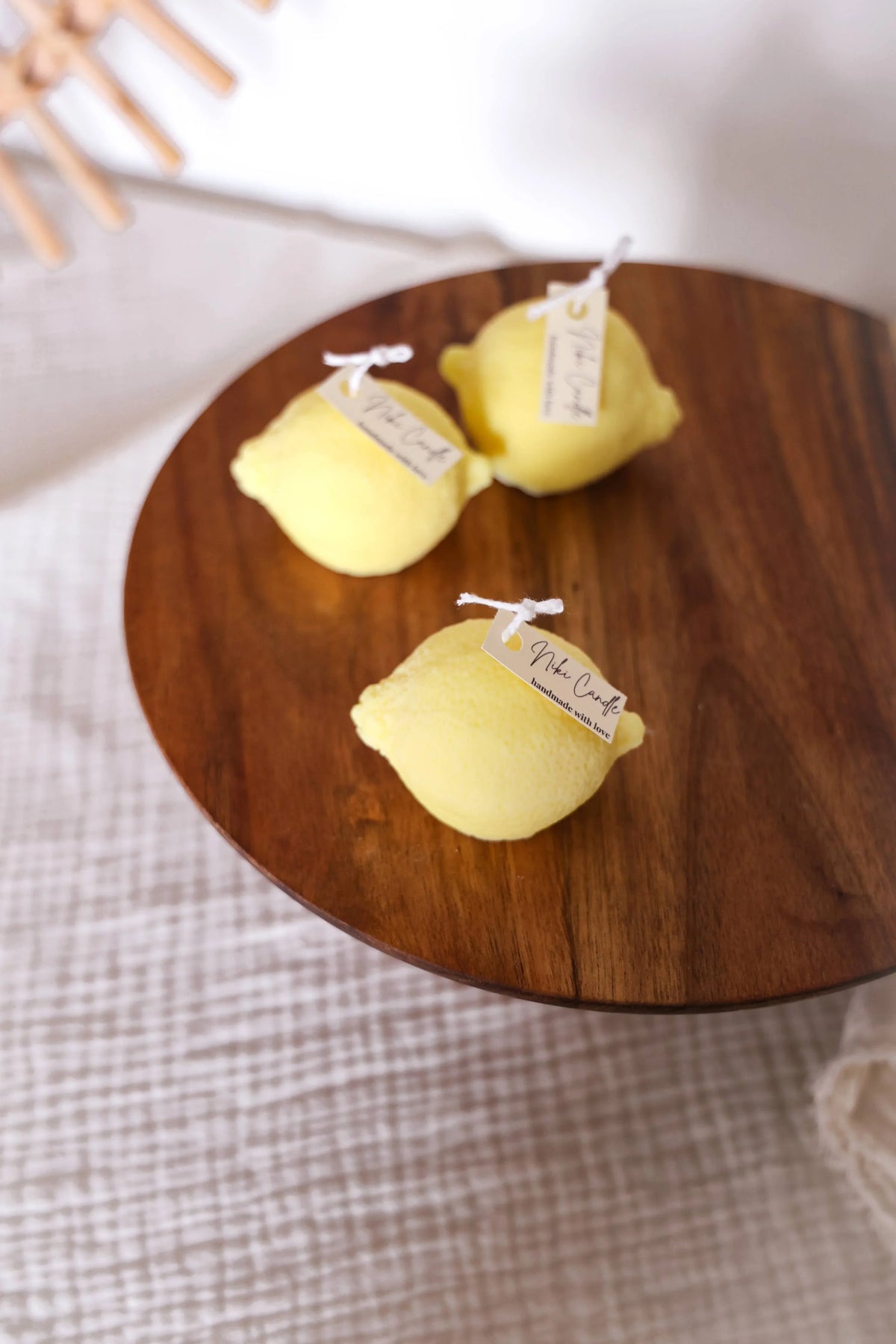 Drie gele citroenkaarsen met labels op een houten bord, zachte achtergrond