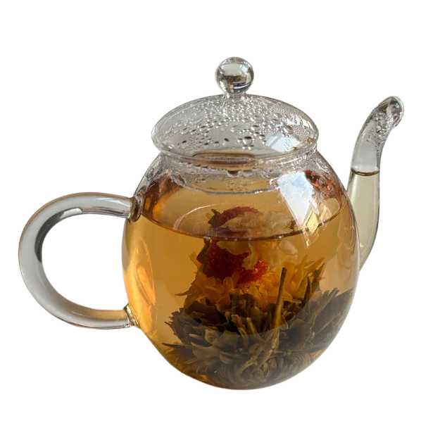 Glazen theepot met bloemvormige theebloem en warme thee, damp op de deksel