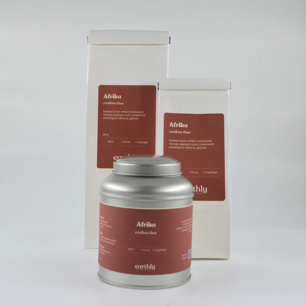 Zilveren theeblik en twee witte zakken met Afrika rooibos thee van Earthly