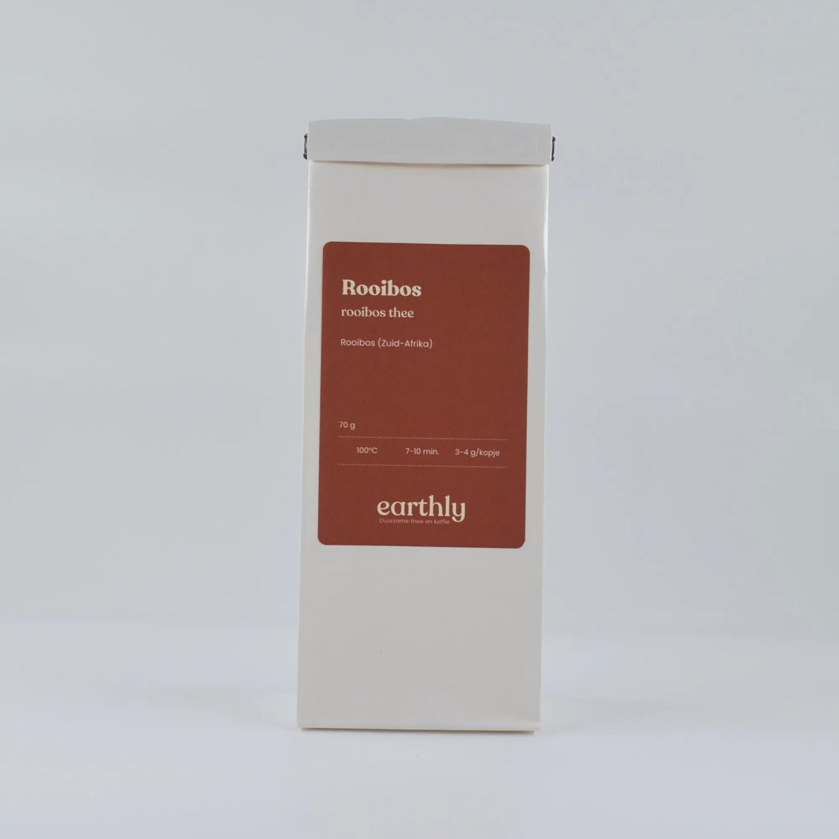 Witte verpakking rooibos thee van Earthly met rood label en infolabel in minimalistische setting