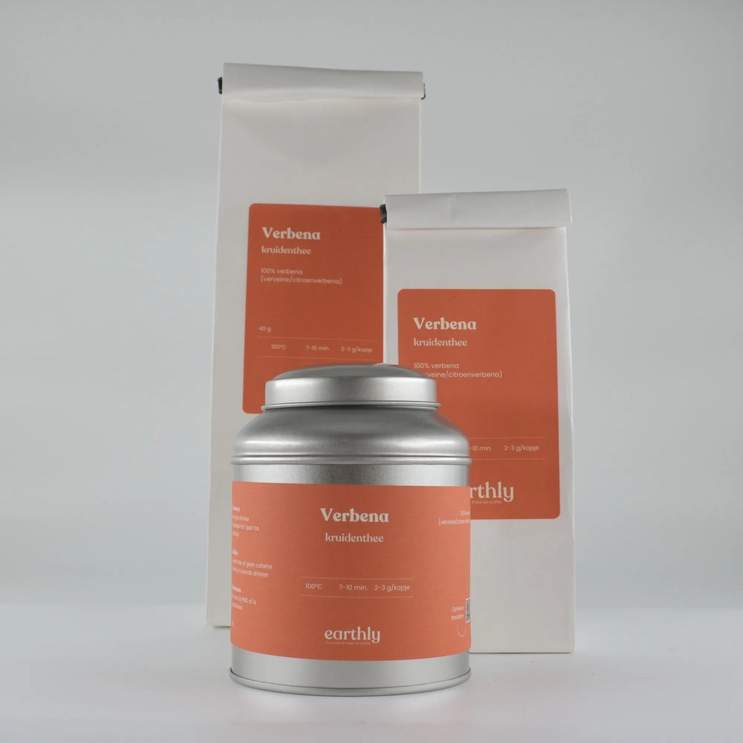Verbena kruidenthee verpakkingen met oranje etiketten en zilveren theeblik, natuurlijke kruidenthee