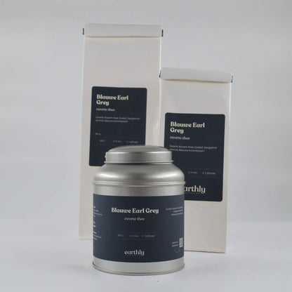 Verpakking van Blauwe Earl Grey zwarte thee van Earthly met blik en zakken tegen witte achtergrond