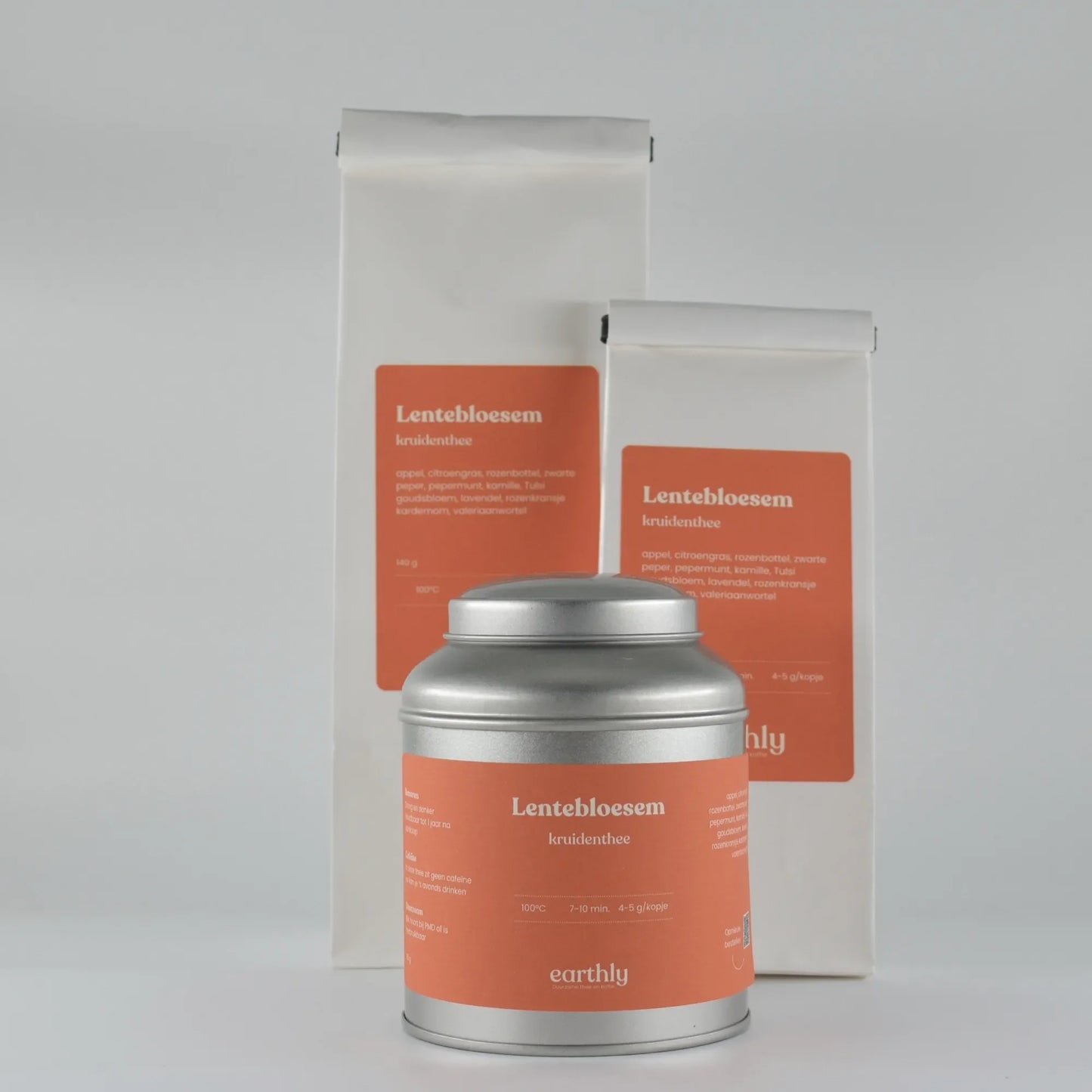 Lentebloesem kruidenthee verpakkingen met oranje etiketten en zilveren theeblik van Earthly