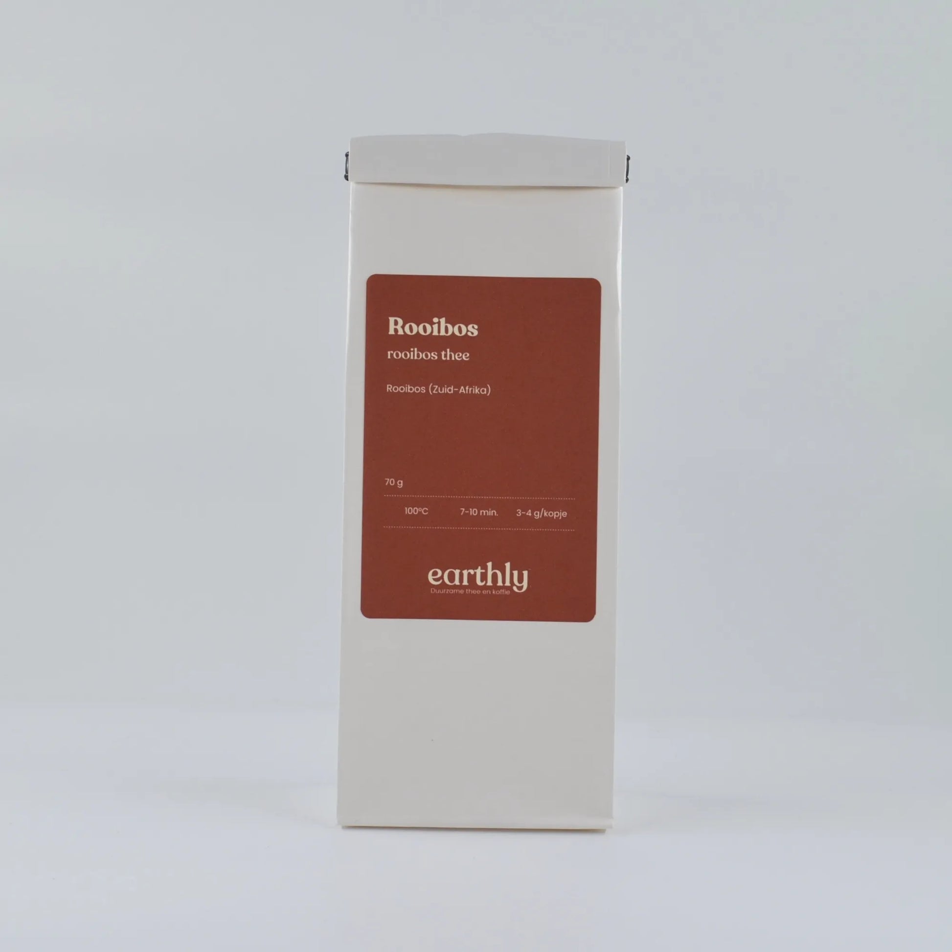 Witte verpakking rooibos thee van Earthly met rood label en infolabel in minimalistische setting