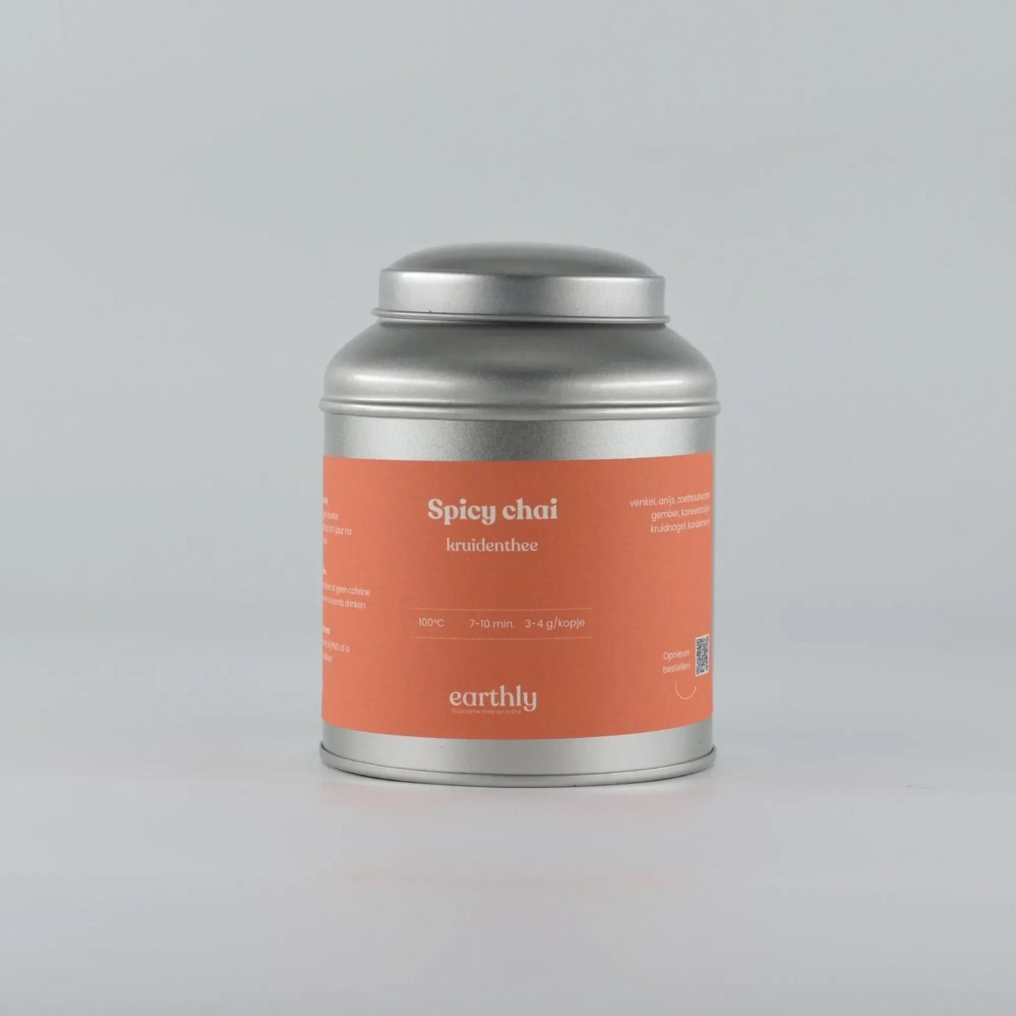 Zilveren theeblik met oranje etiket Spicy Chai kruidenthee van Earthly tegen effen achtergrond