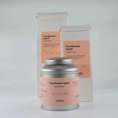 Blik en twee zakken Veenbessen appel vruchtenthee van Earthly met roze labels en informatie